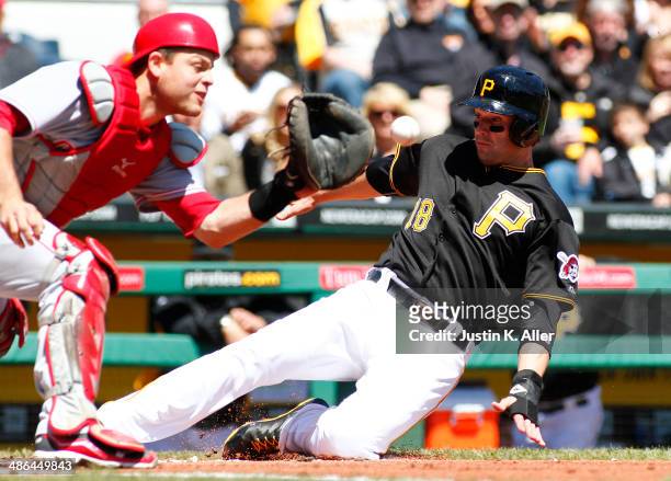 Neil Walker of the Pittsburgh Pirates slides in safe against Devin Mesoraco of the Cincinnati Reds in the first inning during the game at PNC Park...