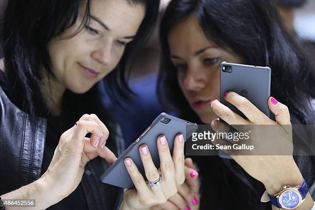 Visitors try out the Honor 7 smartphone at the Huawei stand at the 2015 IFA consumer electronics and appliances trade fair on September 4, 2015 in...