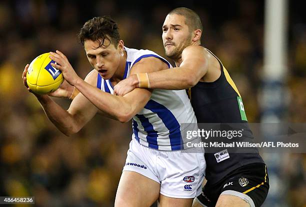 Ben Jacobs of the Kangaroos is tackled by Shaun Grigg of the Tigers during the 2015 AFL round 23 match between the Richmond Tigers and the North...