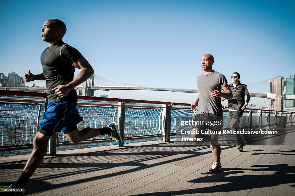 Team running together along waterfront, New York, USA