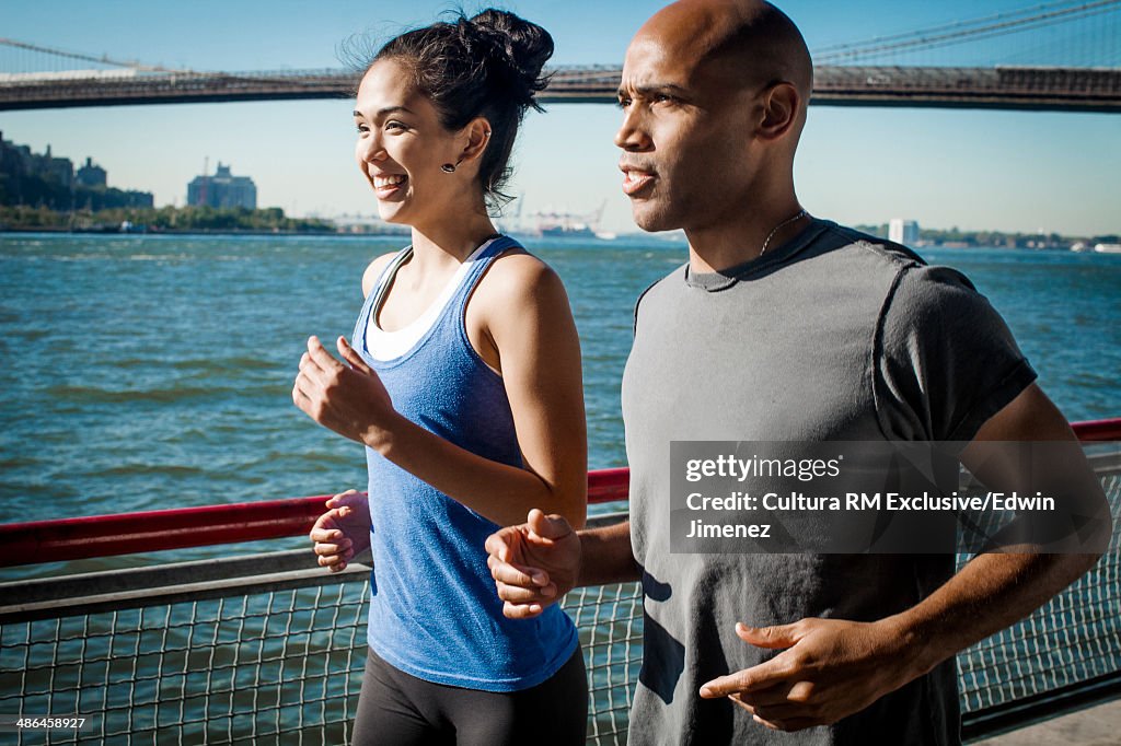 Team mates running along waterfront, New York, USA