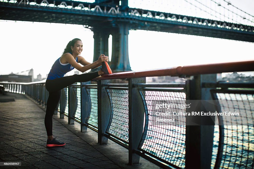 Young female runner stretching, New York City, USA