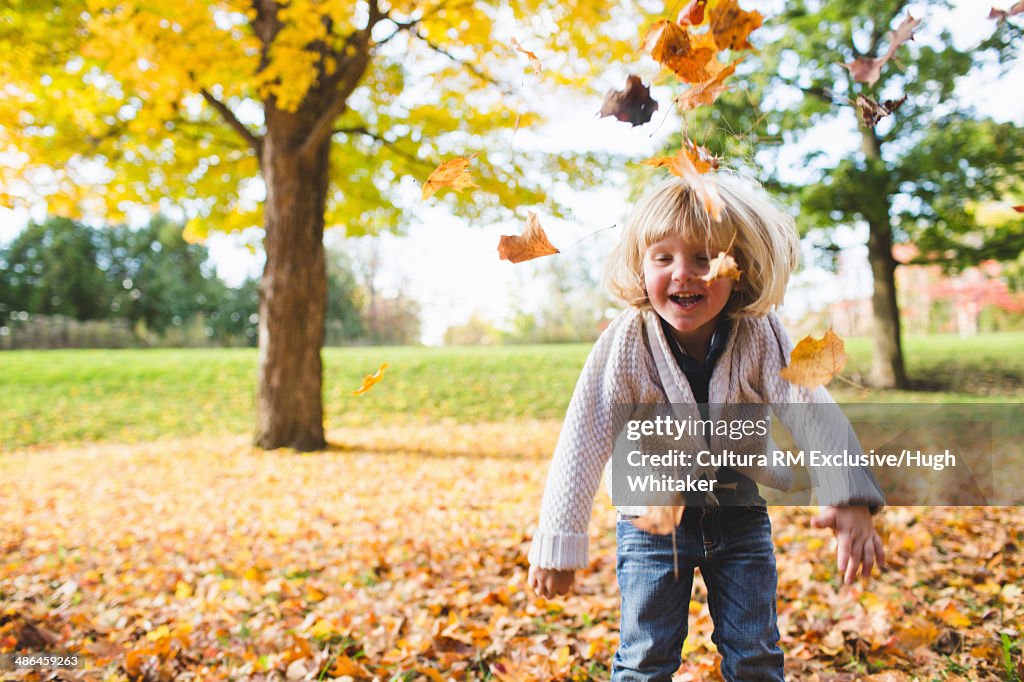 Female toddler playing with autumn leaves