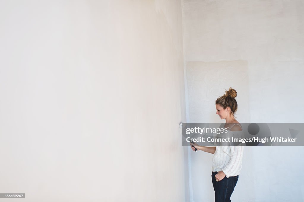 Young woman decorating with a paint roller at home