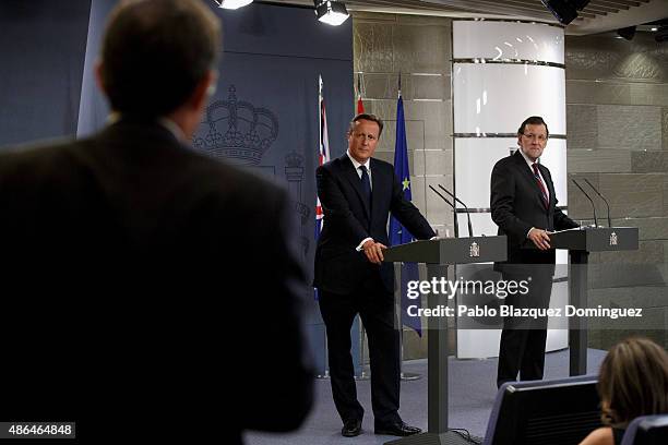 British Prime Minister David Cameron and Spanish Prime Minister Mariano Rajoy look at a journalist as he asks a question during a press conference at...