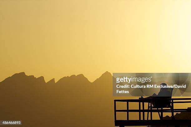 silhouetted person sitting on balcony at sunset, nizwa, oman - hot arabian women stock pictures, royalty-free photos & images