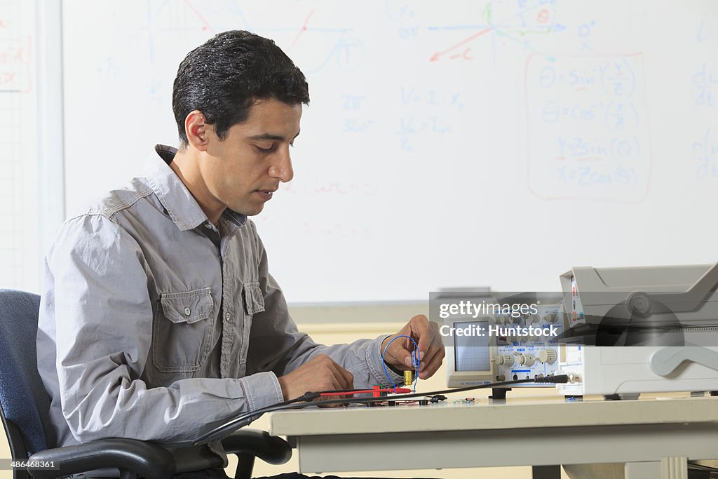 Engineering student inserting component into prototyping breadboard for an electronics lab experiment
