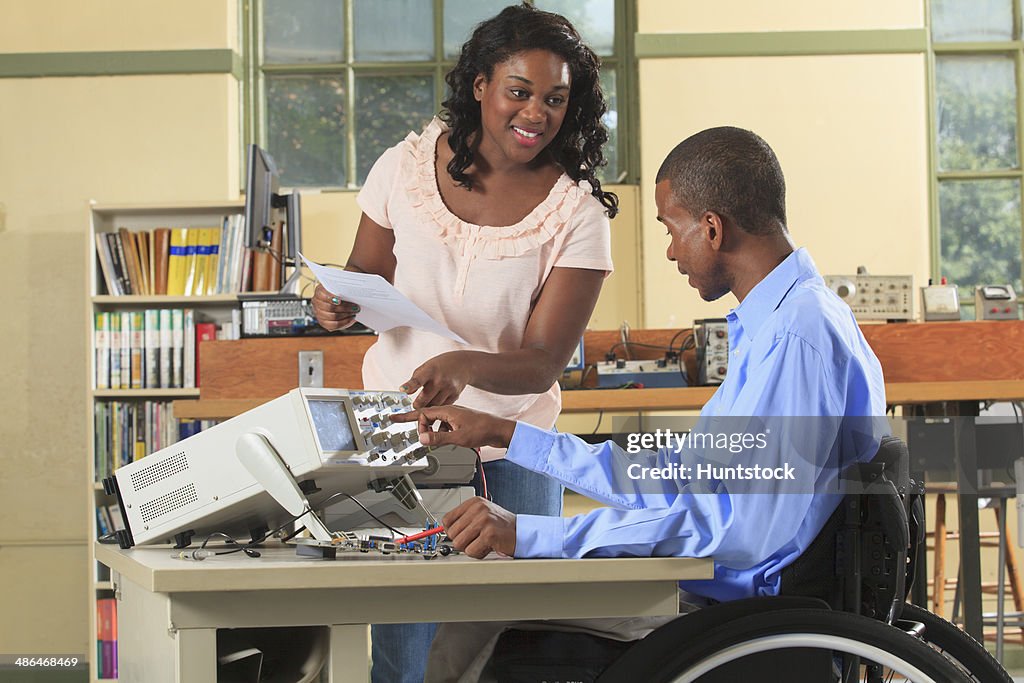 Engineering students in an electronics classroom one in a wheelchair working with an oscilloscope