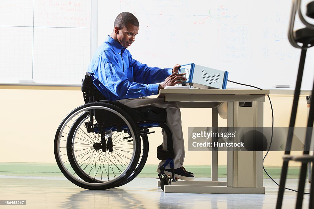 Engineering student in wheelchair from Spinal Meningitis taking measurements from an LCR impedance meter