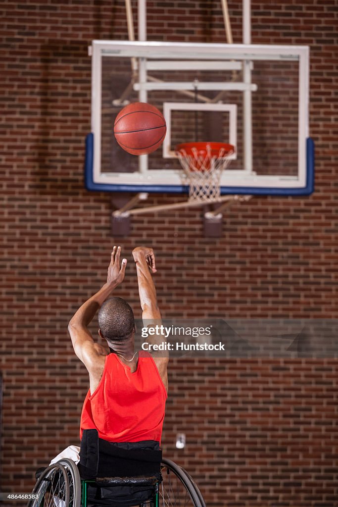 Man who had Spinal Meningitis in wheelchair taking a net shot in basketball