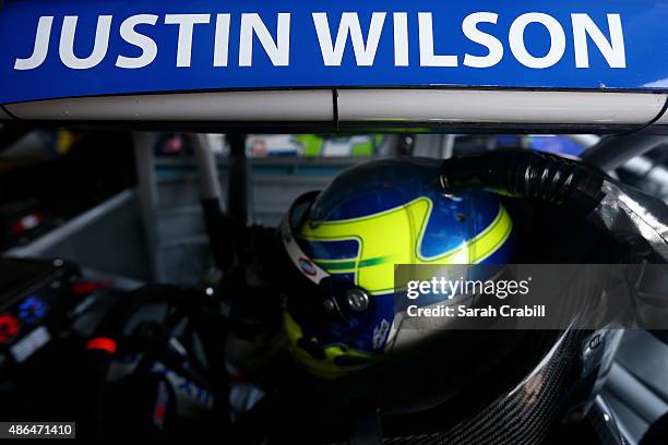 Allmendinger, driver of the Kroger/House-Autry Chevrolet, sits in his car with a tribute to the late IndyCar driver Justin Wilson displayed on his...