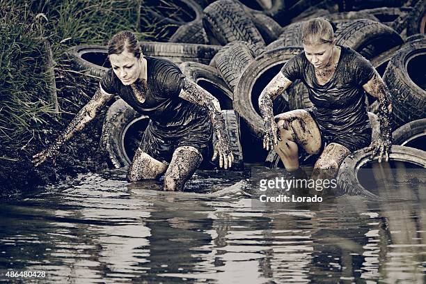 women crossing muddy canal with tires - obstacle course stock pictures, royalty-free photos & images