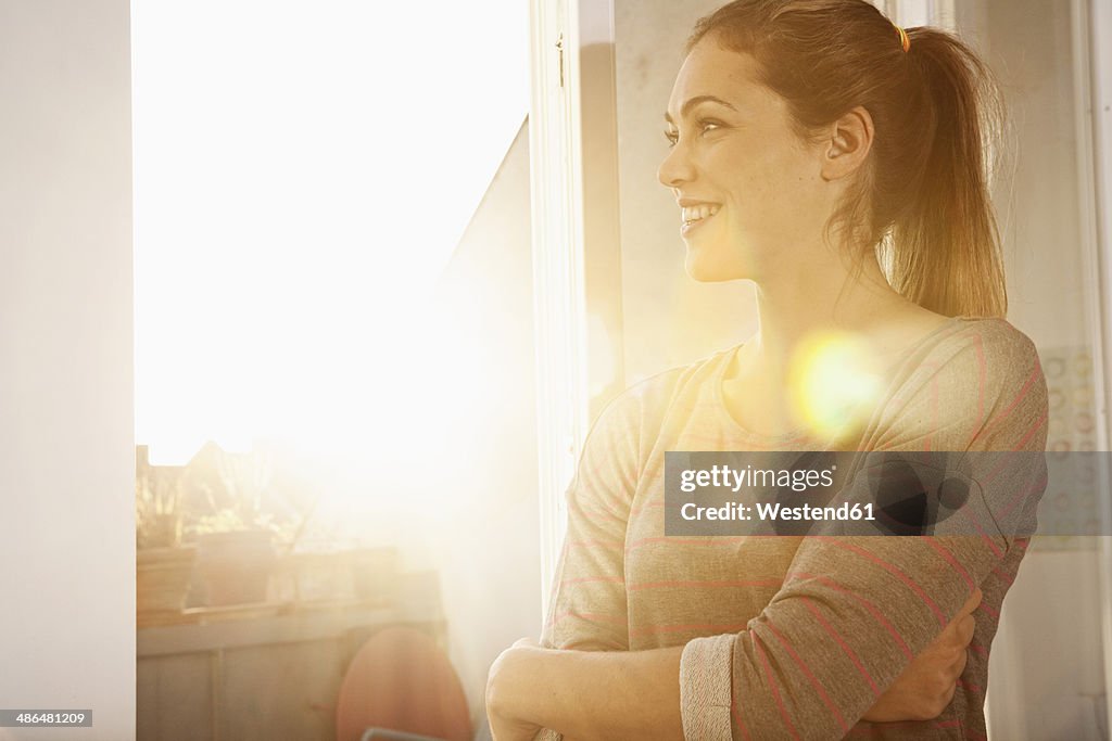 Portrait of happy woman standing at open window