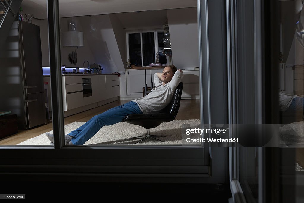 Man at home relaxing in armchair at night