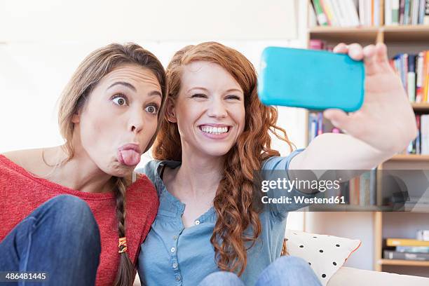 two young female friends taking a picture of themseves with smartphone - puckering ストックフォトと画像