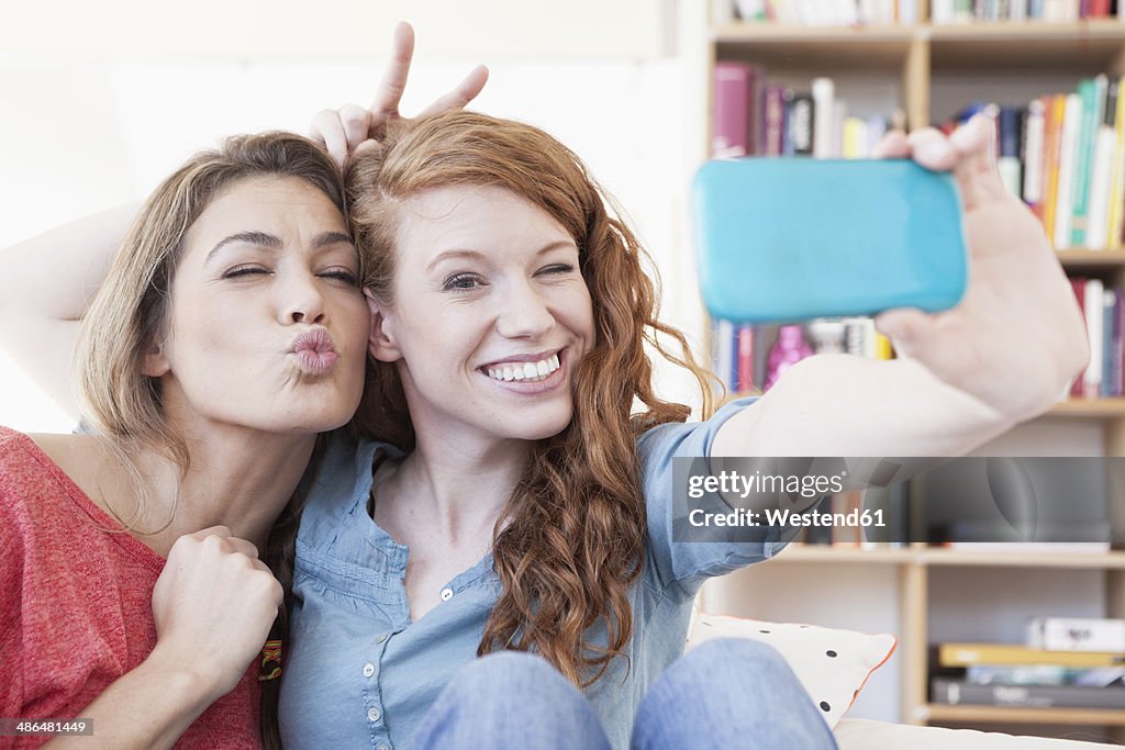 Two young female friends taking a picture of themseves with smartphone