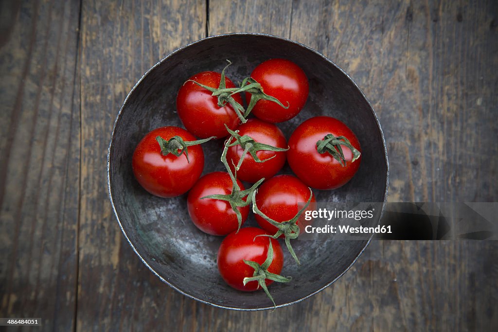 Bowl with cherry tomatoes on wooden table, elevated view