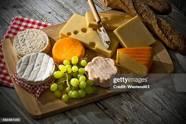 cheese platter, different cheese, french cheddar, french soft cheese, french sheep cheese, camembert, emmentaler, and austrian mountain cheese and wholemeat baguette on wooden board - cheese board photos et images de collection