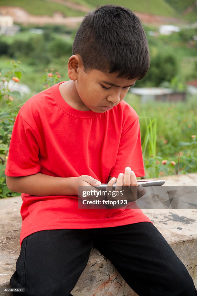 Menino de escola primária, asiática usando tablet digital ao ar livre.