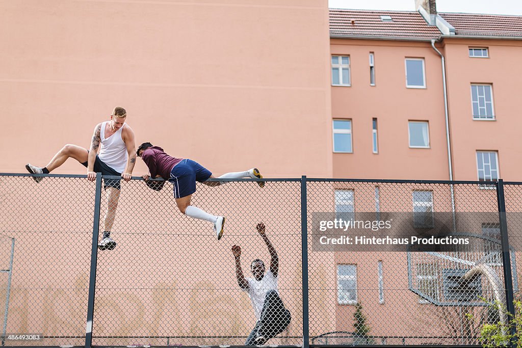 Friends Climbing Over Fence