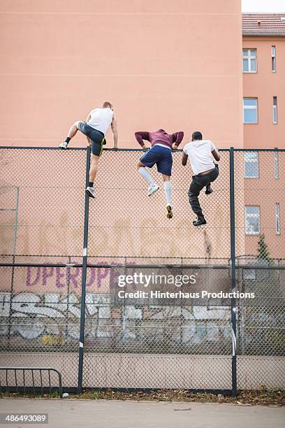 friends climbing over fence - clambering imagens e fotografias de stock