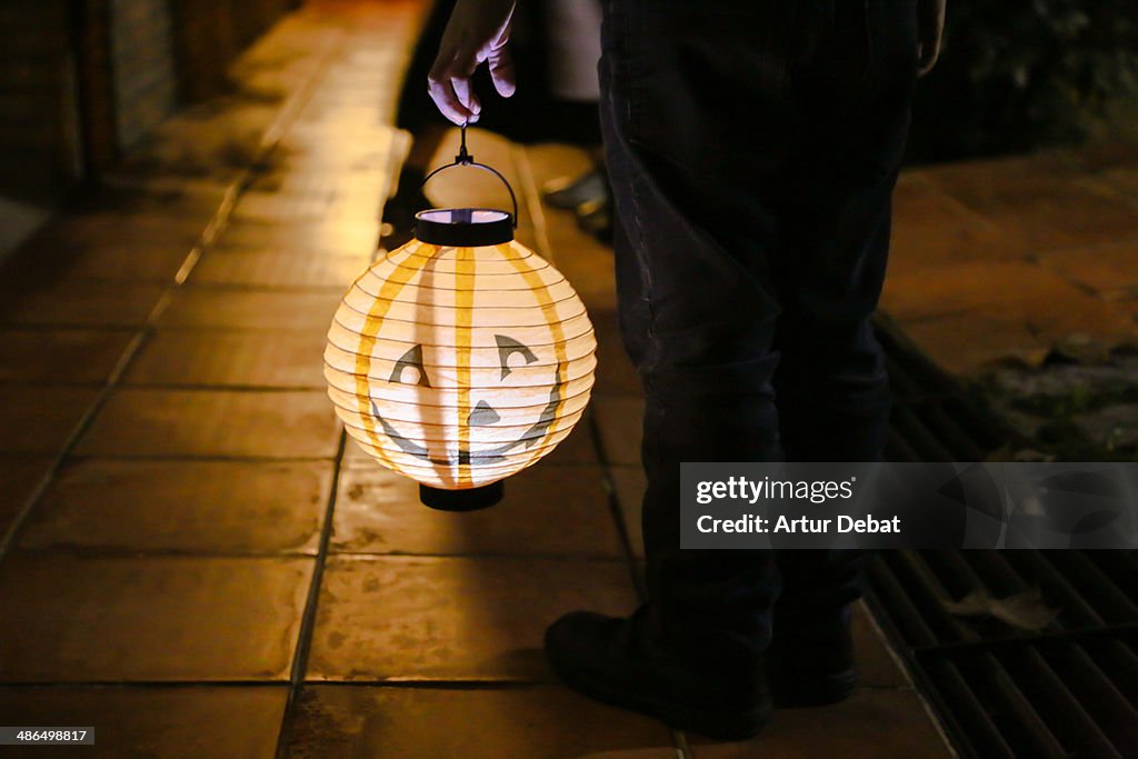 Boy holding a Halloween pumpkin lantern at night