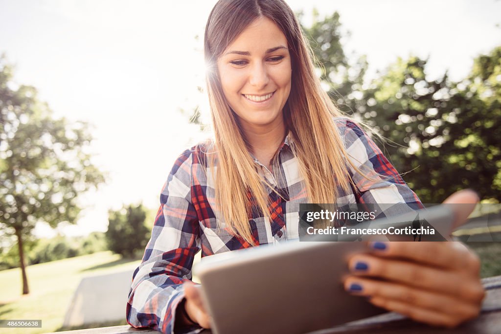 Young woman with digital tablet at the park