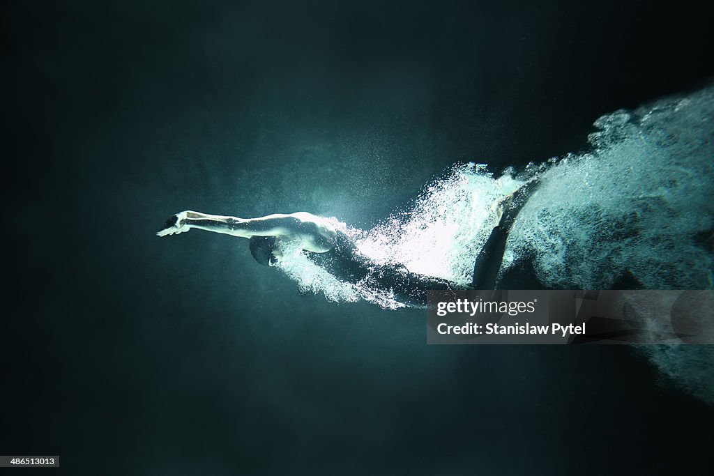 Man swimming underwater on black background