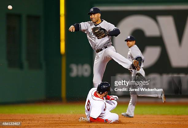Derek Jeter of the New York Yankees turns the double play at second base over Jonny Gomes of the Boston Red Sox in the second inning during the game...