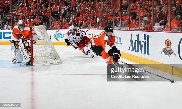 Andrew MacDonald skates the puck behind the net of Ray Emery of the Philadelphia Flyers against Martin St. Louis of the New York Rangers in Game...
