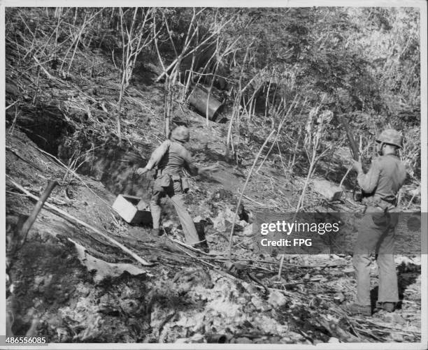 Marine gunnery Sergeant E L Blanchard throwing a hand grenade into a cave where Japanese snipers may be hiding out, during the Pacific Campaign of...