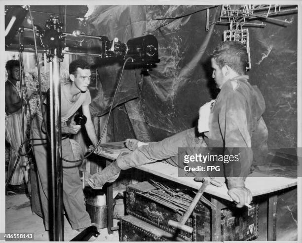 Wounded US Marine getting a foot X-ray at a field medical base, being tended to by Pharmacists Mate First Class Frank E Newkirk, during the Pacific...