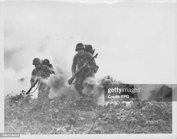 Soldiers of the 29th Infantry moving under smoke cover in field exercises during World War Two, Okinawa, Japan, circa 1941-1945.