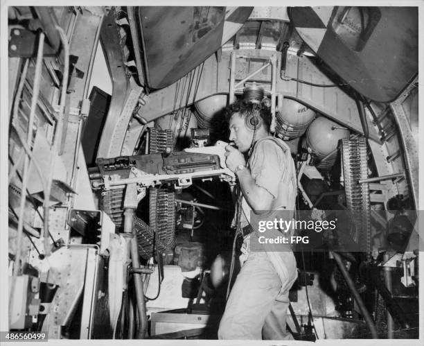 Marine Corporal Robert Borrell firing a 50 caliber machine gun inside a bomber, during the Pacific Campaign of World War Two, Papua New Guinea, circa...