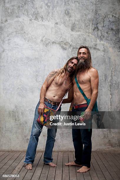 Two male friends smiling w/blank wall w/bags