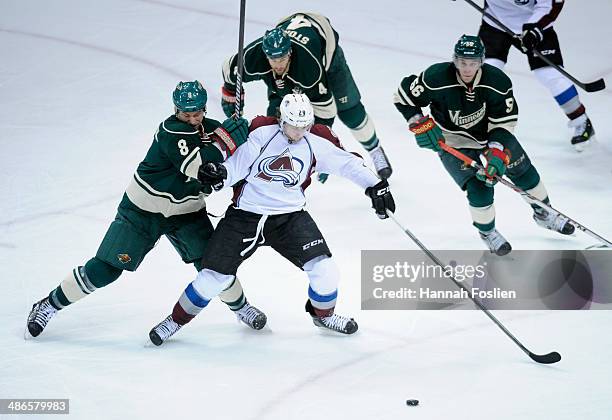 Nathan MacKinnon of the Colorado Avalanche controls the puck against Cody McCormick, Clayton Stoner and Erik Haula of the Minnesota Wild during the...