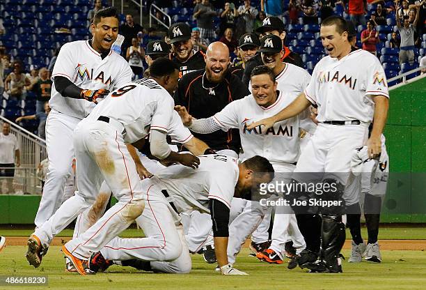 Martin Prado of the Miami Marlins is mobbed by teammates after his game-winning walk-off hit in the 11th inning to defeat the New York Mets 6-5 at...