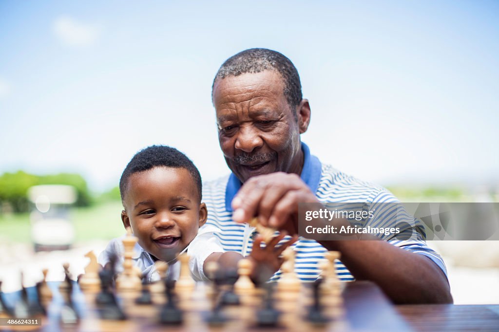 African grandfather playing chess with his grandson