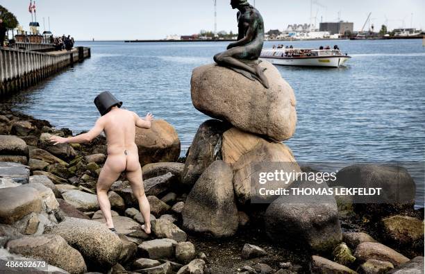 Danish happening and performance artist Uwe Max Jensen walks naked with at bucket on his head in front of the statue of The Little Mermaid in...