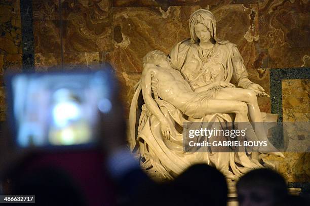 People take pictures of the Michelangelo's Pieta as they visit St Peter's Basilica on April 24, 2014 at the Vatican. AFP PHOTO / GABRIEL BOUYS