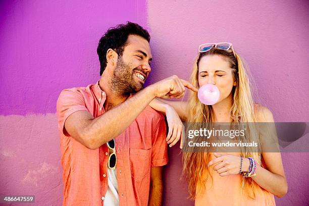 playful man popping chewing gum bubble girl - bubble gum bubble stock pictures, royalty-free photos & images