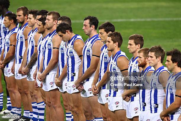Kangaroos players line up for a minutes silence in tribute to Anzac Day during the round six AFL match between the Fremantle Dockers and the North...