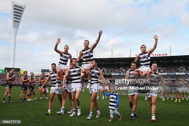 James Kelly is carried off by Jimmy Bartel and Harry Taylor, Steve Johnson of the Cats by Tom Lonergan and Andrew Mackie and Mathew Stokes is carried...