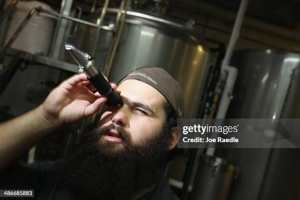 David Rodriguez, a beer brewer, uses a refractometer to determine the sugar mixture in the batch of beer at Wynwood Brewing Company on April 25, 2014...
