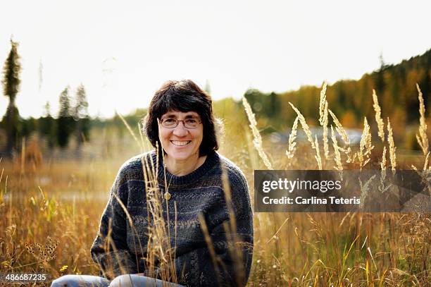 woman in thick sweater sitting in grass - thick white women fotografías e imágenes de stock