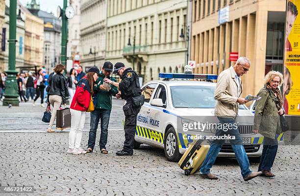 policeman showing direction to asian tourists in prague - prague cafe stock pictures, royalty-free photos & images