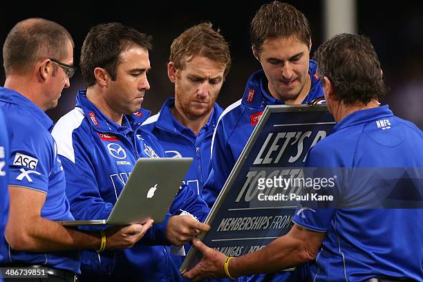 Brad Scott , coach of the Kangaroos adjusts his players positions on the board at the three quarter time break during the round six AFL match between...