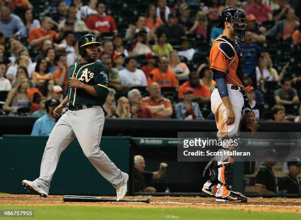 Alberto Callaspo of the Oakland Athletics scores the go-ahead run in the ninth inning as Jason Castro of the Houston Astros looks on during their...