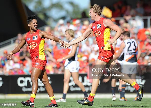 Tom Lynch of the Suns celebrates kicking a goal with Aaron Hall during the round six AFL match between the Gold Coast Suns and the Greater Western...