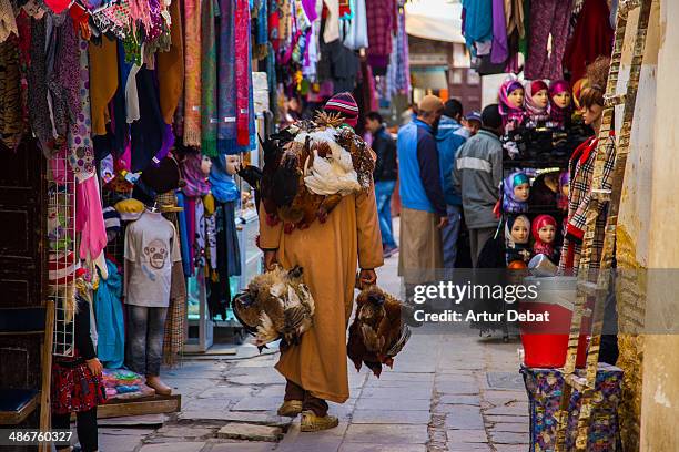 fez medina colorful street and man carrying chiken - fes marokko stock-fotos und bilder